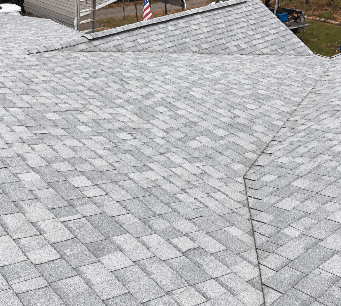 Finished shingle roof viewed toward a brick chimney and adjoining roof planes